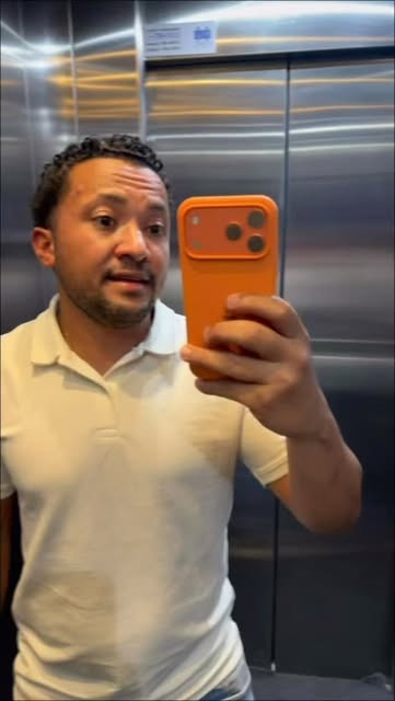 Wellington tira uma foto no espelho do elevador com um aparelho laranja